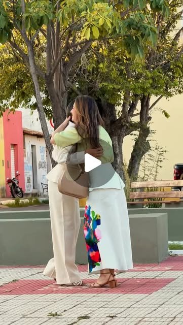 Vídeo da Estelina Magalhães Alfaiataria Feminina com duas mulheres se abraçando na praça